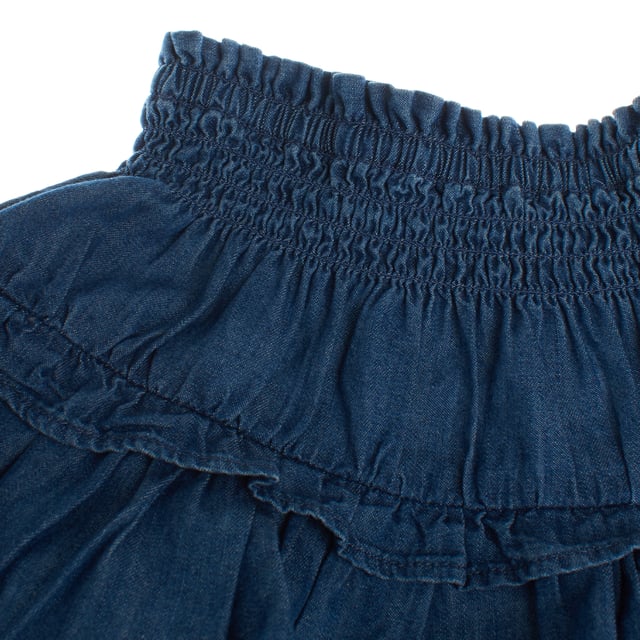 Falda para niñas hecha de denim ligero, con un diseño de cintura elástica fruncida que asegura un ajuste cómodo y adaptable.

La falda destaca por su encantador estilo, con varias capas de volantes que le dan volumen y movimiento, creando un look dinámico y femenino.

Perfecta para combinar con blusas o camisetas, es una prenda versátil que añade un toque divertido y fresco a cualquier conjunto.

Ideal para el uso diario o para ocasiones más especiales, esta falda combina estilo y comodidad de manera impecable.  
Composición: 100% Algodón  
Cuidado:  
- Lavar a máquina en frío.  
- Usar colores similares en el lavado.  
- Evitar el uso de blanqueadores.  
- Secar a baja temperatura en la secadora.  
- Planchar a baja temperatura.  
- No limpiar en seco.