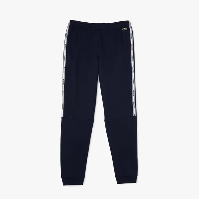 Men's Lacoste Branded Bands Skinny Fleece Joggers.- Brushed cotton blend fleece.- Elasticised waistband.- Tapered fit.- Tapered cut.- Side pockets, ribbed finishes on leg bottoms and Lacoste branding on stripes on sides.- Embroidered green crocodile on hip. Material: 83% Cotton, 17% Polyester. Ref: XH1208166.