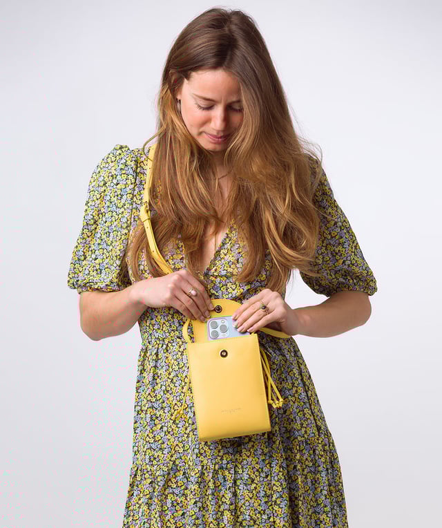 The 'Kiana' cross body phone bag from the Pure Luxuries Marylebone Collection is handcrafted from high-quality, genuine Nappa leather with a natural super-soft touch. The minimalistic fold-over top is secured by a gold-coloured magnetic press stud. This practical design is the perfect place to keep your phone safe and features a tassel design on the exterior. Lined with 100% cotton for a flawless finish and comes with a matching and adjustable slim leather strap with a maximum drop length of 65cm. The minimalist Pure Luxuries logo is embossed in gold foil for a beautifully simple finishing touch.