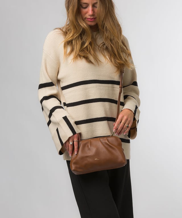 The 'Halsey' cross body clutch bag from Pure Luxuries London's Knightsbridge Collection is handcrafted from gold standard Nappa leather with a super-soft and smooth finish. The zip-over top opens to reveal a 100% cotton interior. The spacious compartment features four card slots to help maintain an organised bag. Comes with an adjustable and removable slim leather strap, with a maximum drop length of 65cm. Features gold-coloured metal fittings and zips. The minimalist Pure Luxuries logo is embossed in gold foil for a beautifully simple finishing touch.