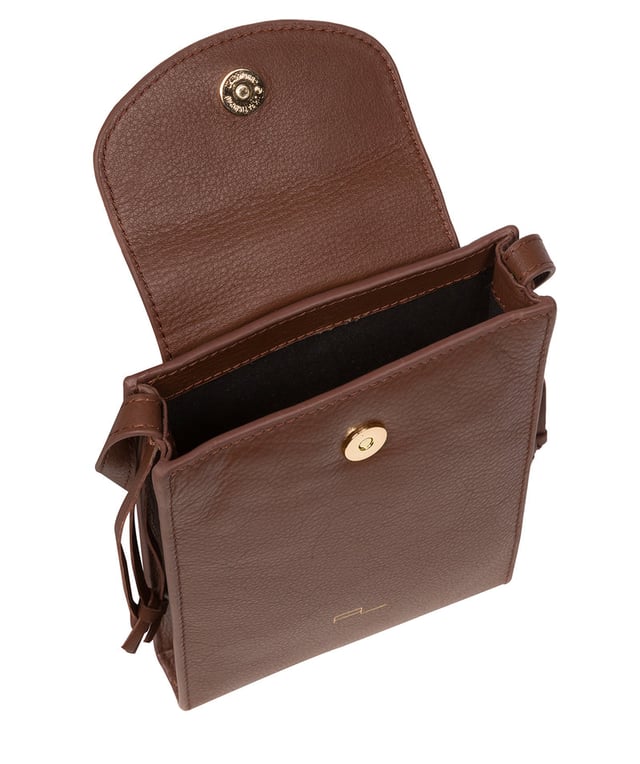 The 'Kiana' cross body phone bag from the Pure Luxuries Marylebone Collection is handcrafted from high-quality, genuine Nappa leather with a natural super-soft touch. The minimalistic fold-over top is secured by a gold-coloured magnetic press stud. This practical design is the perfect place to keep your phone safe and features a tassel design on the exterior. Lined with 100% cotton for a flawless finish and comes with a matching and adjustable slim leather strap with a maximum drop length of 65cm. The minimalist Pure Luxuries logo is embossed in gold foil for a beautifully simple finishing touch.