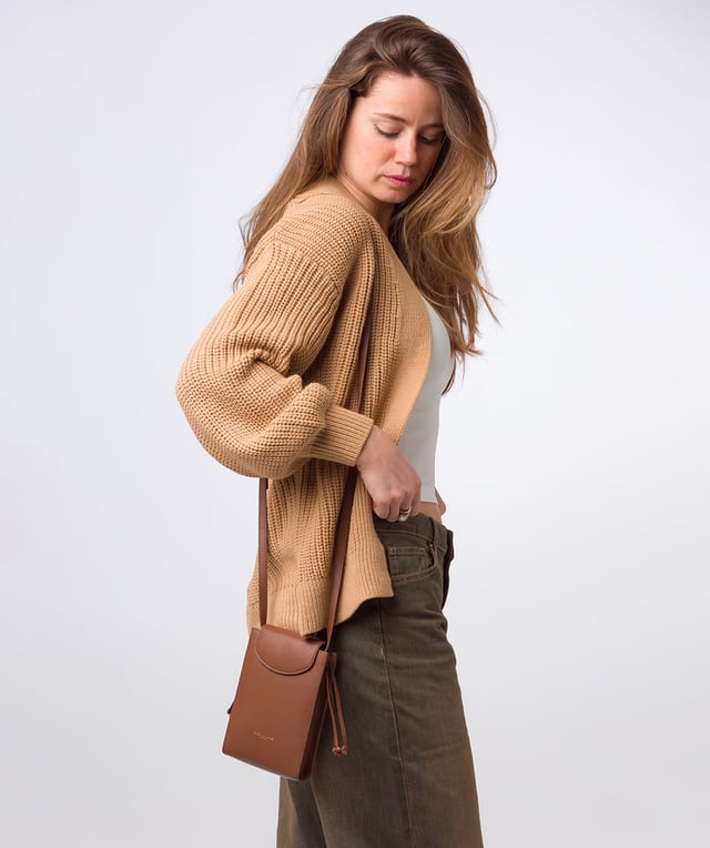 The 'Kiana' cross body phone bag from the Pure Luxuries Marylebone Collection is handcrafted from high-quality, genuine Nappa leather with a natural super-soft touch. The minimalistic fold-over top is secured by a gold-coloured magnetic press stud. This practical design is the perfect place to keep your phone safe and features a tassel design on the exterior. Lined with 100% cotton for a flawless finish and comes with a matching and adjustable slim leather strap with a maximum drop length of 65cm. The minimalist Pure Luxuries logo is embossed in gold foil for a beautifully simple finishing touch.
