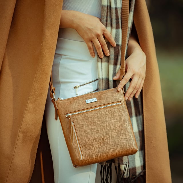 RUE' Soft Pebble Grain Leather Crossbody Bag The Assots timeless design 'Rue' crossbody bag is beautifully handcrafted from the finest & softest pebble grain genuine leather. Effortlessly stylish, this real leather crossbody features four zip pockets to organise your essentials when you're out and about. Ideal as an everyday bag, the 'Rue' is a must-have addition to your collection of luxurious leather handbags. Secured zip top closure opens to a fully lined and roomy interior. Pure cotton fabric lining used in natural beige making it a free from plastic product. Secured two zip pockets at the front to slide in your essentials such as face covering, smart phone and more. Back zip pocket for quick and easy access to your essentials. Adjustable long cotton webbing shoulder strap handle for a comfortable carry. Lightweight. Adorned with the inimitable Assots London clean finish silver metal logo at the front. Fittings colour: Silver Nickel. Composition: Body: 100% Genuine Leather. Lining: Pure Cotton. DISCLAIMER: All pictures shown are for illustration purposes only. Actual product colour may vary due to different ambience lighting or the screen display settings. Size- W22cm x H21cm x D3cm.