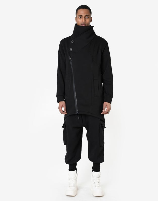 La Haine Inside Us Mantel Unisex Damen schwarz Dieser einfarbige Pullover ist ein echter Klassiker, der perfekt in jede Garderobe passt und jeder Outfit-Einstellung Eleganz und Stil verleiht.
Dank eines längeren Schnitts sieht der Pullover nicht nur besonders modisch aus, sondern bietet auch zusätzliche Wärme und Komfort an kühleren Tagen, indem er vor Wind und Regen schützt.
Die mit einem Reißverschluss verschließbare Konstruktion macht den Pullover extrem praktisch und einfach anzuziehen, während sie gleichzeitig garantiert, dass Sie immer ordentlich und stilvoll aussehen.
Ein zusätzlicher Kragen, der mit Knöpfen geschlossen wird, ist nicht nur ein funktionales Element, das vor Kälte schützt, sondern auch ein stilvolles Detail, das dem Pullover einen einzigartigen Charakter verleiht.
Hergestellt in Italien, was eine Garantie für höchste Materialqualität und präzise Verarbeitung ist, charakteristisch für italienisches Handwerk und Design.