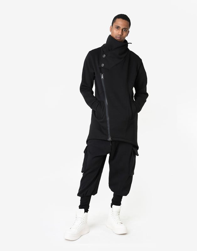 La Haine Inside Us Mantel Unisex Damen schwarz Dieser einfarbige Pullover ist ein echter Klassiker, der perfekt in jede Garderobe passt und jeder Outfit-Einstellung Eleganz und Stil verleiht.
Dank eines längeren Schnitts sieht der Pullover nicht nur besonders modisch aus, sondern bietet auch zusätzliche Wärme und Komfort an kühleren Tagen, indem er vor Wind und Regen schützt.
Die mit einem Reißverschluss verschließbare Konstruktion macht den Pullover extrem praktisch und einfach anzuziehen, während sie gleichzeitig garantiert, dass Sie immer ordentlich und stilvoll aussehen.
Ein zusätzlicher Kragen, der mit Knöpfen geschlossen wird, ist nicht nur ein funktionales Element, das vor Kälte schützt, sondern auch ein stilvolles Detail, das dem Pullover einen einzigartigen Charakter verleiht.
Hergestellt in Italien, was eine Garantie für höchste Materialqualität und präzise Verarbeitung ist, charakteristisch für italienisches Handwerk und Design.