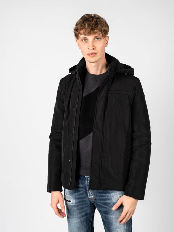 El diseño sencillo de esta chaqueta es la combinación perfecta de elegancia y comodidad, lo que hace que sea adecuada tanto para atuendos cotidianos como para estilismos más formales, y su corte minimalista realza el carácter moderno.

Con una capucha desmontable que proporciona protección adicional contra el viento y la lluvia, la chaqueta se convierte en una opción versátil para cualquier clima, ofreciendo al mismo tiempo la posibilidad de adaptarse a las necesidades individuales del usuario.

Cerrada con una cremallera logotipada y botones a presión, la chaqueta combina funcionalidad con un estilo único, añadiendo un sutil toque de la marca que seguramente atraerá la atención de los amantes de la moda.

En el frente tiene cuatro bolsillos, dos con cremallera y dos con botones a presión, que ofrecen soluciones prácticas para almacenar elementos esenciales, garantizando al mismo tiempo un acceso fácil y seguridad.

En la manga izquierda, un detalle de la empresa es un toque discreto pero elegante, que le da carácter a la chaqueta y subraya su exclusividad, permitiendo destacar entre la multitud.

Confeccionada con tejido de alta calidad, transpirable y resistente al agua, la chaqueta proporciona confort y protección en cualquier condición climática, cuidando al mismo tiempo de la adecuada circulación del aire y manteniendo la temperatura óptima del cuerpo.