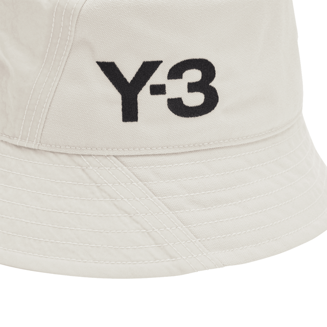 Y-3 klassieke emmerhoed in talk. De bucket hat is synoniem aan street fashion en combineert een gepolijste stijl met casual gemak. Deze versie van Y-3 blijft trouw aan zijn oorsprong, maar voegt opvallende accenten toe. Een monochroom Y-3 logo maakt de look compleet.- Een Y-3 bucket hat.- Oogjes voor ventilatie.- Zweetband aan de binnenkant.- Y-3 logo.- Hoofdmateriaal: 100% polyester (gerecycled).  Voering: 100% nylon (gerecycled).  Handwas koud.- Ref: H62985