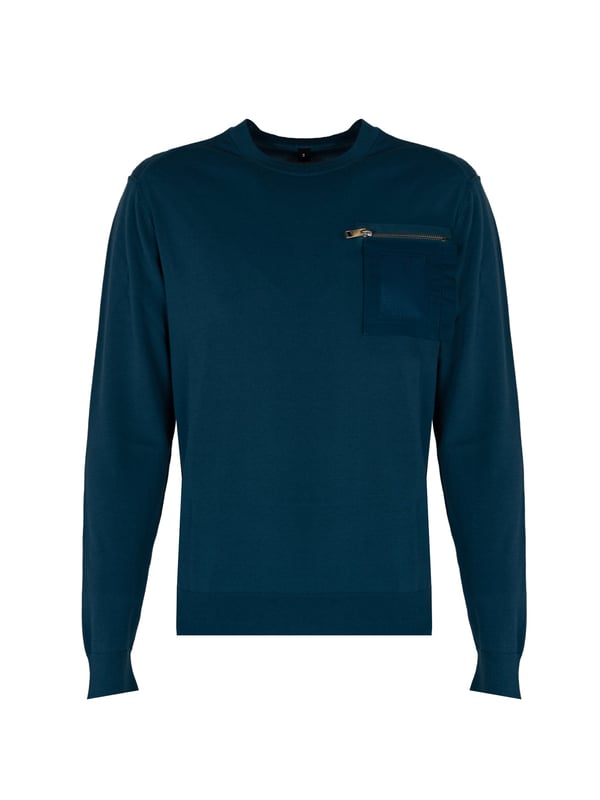 Un suéter fino es la elección perfecta para los días más frescos, ofreciendo un calor sutil sin carga innecesaria, y su diseño ligero hace que funcione bien tanto como una prenda por sí sola como una capa debajo de una chaqueta.

El color uniforme del suéter le añade elegancia y versatilidad, facilitando su combinación con diferentes estilos, desde casual hasta más formal, presentándote siempre de manera moderna y con clase.

Un bolsillo en el pecho con cierre es un añadido práctico que no solo añade estilo, sino que también permite guardar de forma segura objetos pequeños como llaves o tarjetas, siendo al mismo tiempo un acento estilístico.

Los puños elásticos en las muñecas y en la cintura aseguran confort y un ajuste perfecto, protegiendo eficazmente contra el viento y añadiendo al suéter un aspecto moderno que realza la silueta.

Un detalle de marca en la banda de la cintura es un acento sutil pero llamativo que resalta el prestigio y la calidad del producto, dándole un carácter único y distinguiéndolo de otros suéteres.

Las costuras visibles y estilosas añaden al suéter un encanto especial y profundidad, creando una textura interesante que atrae la mirada y demuestra la atención al detalle y la precisión en la confección.

Hecho de materiales de alta calidad, el suéter no solo garantiza durabilidad, sino también comodidad al llevarlo, permitiendo que la piel respire y asegurando un excelente bienestar durante todo el día.