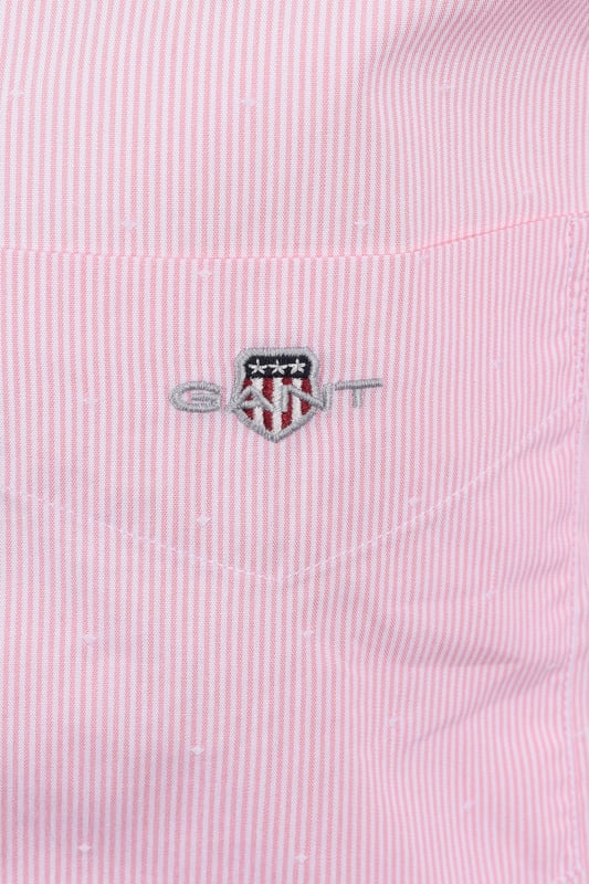 Gant Reg Dobby Dot Stripe Shirt in Geranium Pink
Elevate your casual style with the Gant Reg Dobby Dot Stripe Shirt in a vibrant geranium pink. This shirt is expertly crafted from premium 100% cotton, offering exceptional comfort and breathability throughout the day. The unique dobby dot and yarn-dyed stripe design adds a touch of texture and visual interest, making it a standout piece in your wardrobe.   
 
Designed for a classic regular fit, this shirt features a timeless button-down collar, a practical chest pocket, and adjustable cuffs for a personalised feel. The curved hem ensures a clean and polished look, whether worn tucked or untucked.   
 
Attention to detail is paramount, with recycled polyester buttons contributing to a more sustainable approach. A subtle yet iconic GANT shield graphic is embroidered at the chest, signifying the brand's heritage and quality.
 
Features

100% Premium Cotton
Dobby Dot and Yarn-Dyed Stripe Design
Regular Fit
Button-Down Collar
Chest Pocket
Adjustable Cuffs
Curved Hem
Recycled Polyester Buttons
Embroidered GANT Shield Graphic
Style code: 3250081