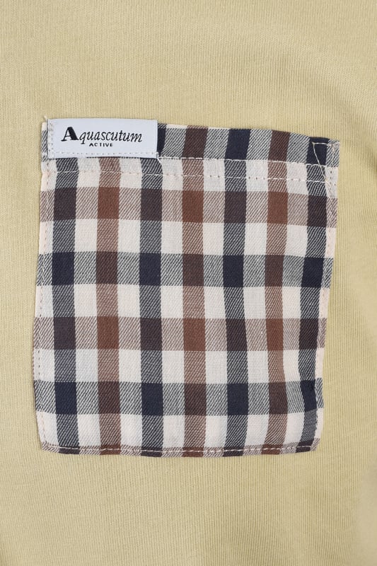 Aquascutum Club Check Pocket T-shirt in Beige
Elevate your casual wardrobe with the Aquascutum Club Check Pocket T-Shirt, crafted for discerning style and sustainable comfort. This beige t-shirt is meticulously made from 100% organic cotton, offering a soft, breathable 180gr/m2 fabric that's gentle on the skin and the environment.
A signature touch of sophistication is delivered through the iconic Aquascutum club check pocket, providing a distinctive contrast against the smooth beige backdrop. A subtly woven logo label on the pocket adds a refined detail, showcasing the brand's heritage.
 
Designed for everyday ease, this t-shirt features a classic crew neck with a durable 1:1 rib knit, short sleeves, and a comfortable regular fit. Whether you're relaxing at home or out for a casual outing, this t-shirt ensures effortless style and lasting comfort.

 
Features

Premium Organic Cotton: Crafted from 100% organic cotton, 180gr/m2, for superior comfort and sustainability.   
Iconic Club Check Pocket: Features a contrasting club check pocket, a hallmark of Aquascutum design.   
Woven Logo Detail: A subtle woven logo label on the pocket adds a touch of brand authenticity.
Classic Crew Neck: Designed with a comfortable 1:1 rib-knit crew neck.   
Regular Fit: This style offers a relaxed and comfortable fit for everyday wear. 
Short Sleeves: Perfect for warm weather or layering.
Style code: AA_B005_TS007