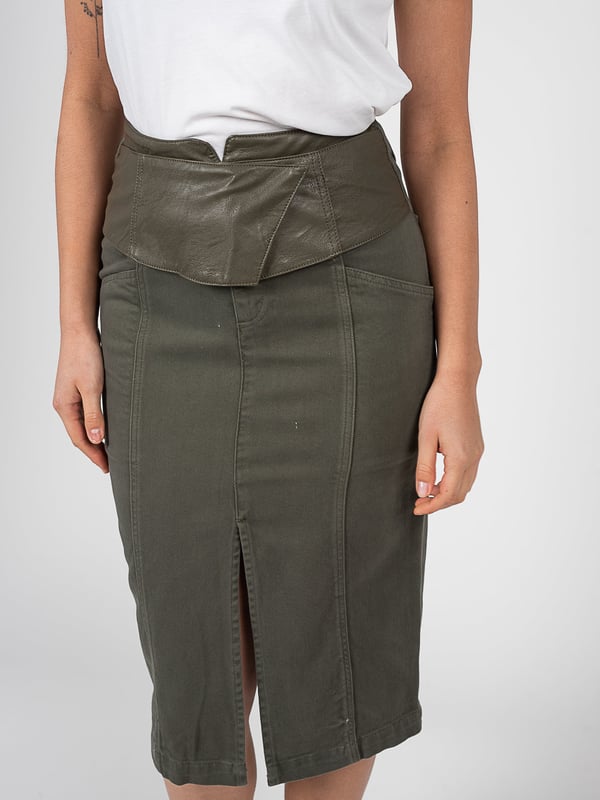 El corte ajustado de esta falda acentúa la silueta, agregando elegancia y confianza, lo que la hace perfecta tanto para ocasiones formales como informales.

La longitud midi asegura versatilidad y comodidad en el uso, permitiendo moverse libremente, al mismo tiempo que añade un toque de chic clásico a cualquier outfit.

Se abrocha con cremallera en la parte delantera, lo que no solo facilita ponérsela, sino que también añade un toque moderno que se integra perfectamente en el diseño general.

Además, el cinturón incluido permite un ajuste personalizado en la cintura, resaltándola y agregando un acabado elegante a cualquier conjunto.

Con dos bolsillos en el frente y la parte trasera, ofrece funcionalidad y practicidad, perfectos para guardar objetos pequeños, como llaves o celular, sin necesidad de llevar un bolso.

El corte decorativo en el frente añade una sutil sensualidad y ligereza, destacando las piernas y otorgando a la falda un carácter único.

Fabricada con tejidos de alta calidad que aseguran durabilidad y comodidad en su uso, a la vez que añaden elegancia y una apariencia de lujo que impresionará a todos.