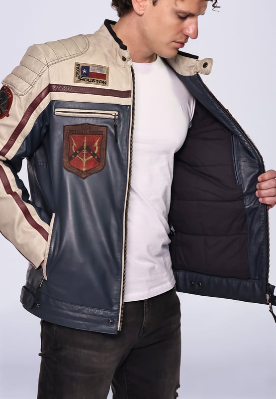 Top Gun Lederjacke TGJ1005 Die Jacke ist mit einem Baumwollfutter ausgestattet und mit den typischen Stickereien. Mit Reißverschlüssen an den Ärmeln und zwei verstellbaren Lederriemen an den Seiten ergibt sich eine ideale Passform. Zwei Seitentaschen mit Reißverschluss und eine Innentasche mit Klettverschluss bieten viel Stauraum. Die Jacke wird über einen geraden Reißverschluss geschlossen und kann zusätzlich über Druckknöpfe am Saum und Kragen geschlossen werden.