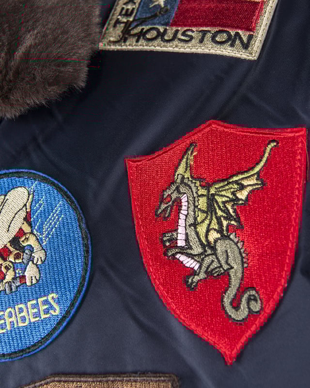 Der einzigartige Top Gun Stil spiegelt sich in dieser hippen Nylonjacke. Sie ist gut gefüttert und besitzt die typische Ärmeltasche mit Reißverschluss - so lässt sich das Tragen dieser Jacke an Lässigkeit kaum überbieten. Der elastische Strick am Ärmelabschluss, Bund und am Kragen sorgt für eine ideale Passform. Optisch ansprechende Stickereien und ein weiches Innenfutter mit Bild schmücken diese Jacke. Zwei seitliche Taschen zum Einschieben mit Knopfverschluss bieten viel Stauraum. Hierfür sind im Inneren zwei zusätzliche Taschen verarbeitet. Diese Jacke ist der absoluter Hingucker für die kalte Jahreszeit.