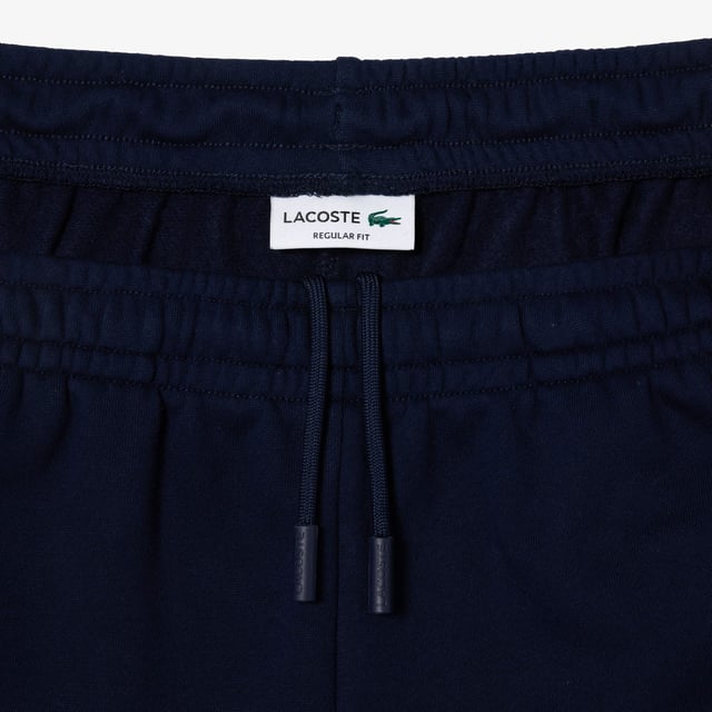 Lacoste Regular Fit Brushed Fleece Colourblock Jogger Shorts. Sporty colorblock shorts with a hip design and functional cut. Graphic style, soft texture. Urban pieces for contemporary looks, signed Lacoste.- Regular fit, straight cut.- Drawstring waist.- Side pockets.- Embroidered crocodile on front. Material: 80% Cotton, 20% Polyester. Ref: GH1319PIG.