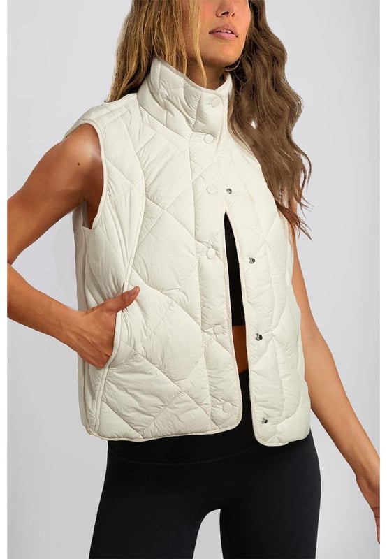 Chaleco acolchado de cuello alto en color beige con botones y bolsillos  
Diseño de cuello alto para mayor aislamiento y una apariencia elegante  
El diseño acolchado ofrece tanto moda como calidez  
Botonadura frontal para un uso fácil y un ajuste seguro  
Ideal para combinar con un suéter y jeans para un look acogedor  
Disponible en varias tallas: S M L XL 2XL  
Material: 100% Poliamida