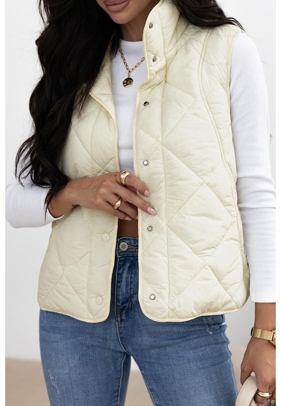 Chaleco acolchado de cuello alto en color beige con botones y bolsillos  
Diseño de cuello alto para mayor aislamiento y una apariencia elegante  
El diseño acolchado ofrece tanto moda como calidez  
Botonadura frontal para un uso fácil y un ajuste seguro  
Ideal para combinar con un suéter y jeans para un look acogedor  
Disponible en varias tallas: S M L XL 2XL  
Material: 100% Poliamida