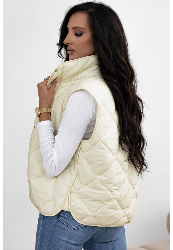 Chaleco acolchado de cuello alto en color beige con botones y bolsillos  
Diseño de cuello alto para mayor aislamiento y una apariencia elegante  
El diseño acolchado ofrece tanto moda como calidez  
Botonadura frontal para un uso fácil y un ajuste seguro  
Ideal para combinar con un suéter y jeans para un look acogedor  
Disponible en varias tallas: S M L XL 2XL  
Material: 100% Poliamida