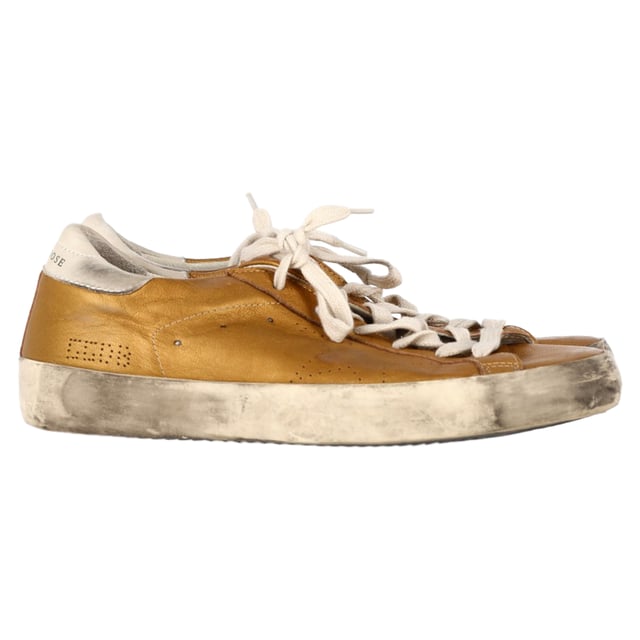 VINTAGE, RRP AS NEW
Add a touch of luxury to your casual wardrobe with the Golden Goose Superstar Perforated Sneakers in gold leather. These sneakers combine effortless street style with high-end craftsmanship, featuring a perforated design that enhances breathability and a sleek metallic gold finish that makes a bold statement. The signature distressed detailing gives them a cool, lived-in look, while the comfortable sole ensures all-day wearability.

Styling Tip: These versatile sneakers pair perfectly with everything from casual jeans and a tee to a chic midi dress for a laid-back yet stylish contrast. For an elevated street style look, pair them with leather leggings or a cropped denim jacket. Whether you're running errands or out for a coffee date, the Golden Goose Superstar sneakers will effortlessly add a touch of glam to any outfit.

 Golden Goose Superstar Perforated Sneakers in Gold Leather

Condition: Excellent
Signs of wear: No visible sign of wear. No Mark at insole.,  Very light mark at soles.
Packaging: None
Color: Gold
Material: Leather | leather
Size: EU | 38
Measurements: Heel height: 30; Insole length: 280
SKU: NAPPUGBSH458415W