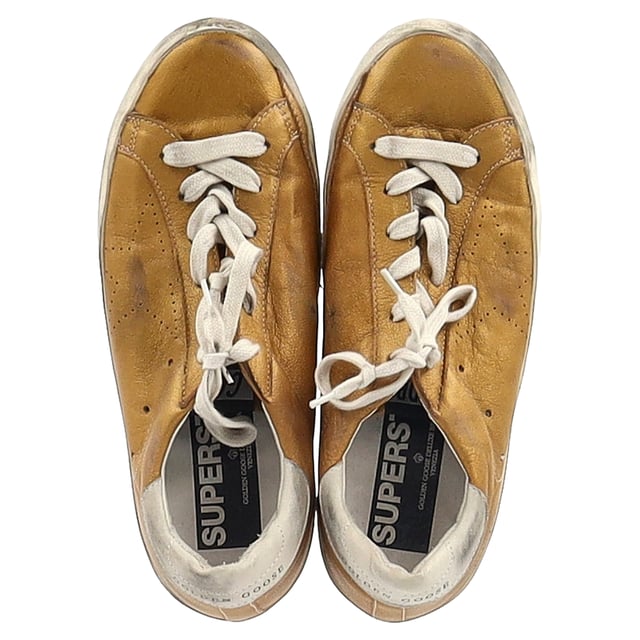 VINTAGE, RRP AS NEW
Add a touch of luxury to your casual wardrobe with the Golden Goose Superstar Perforated Sneakers in gold leather. These sneakers combine effortless street style with high-end craftsmanship, featuring a perforated design that enhances breathability and a sleek metallic gold finish that makes a bold statement. The signature distressed detailing gives them a cool, lived-in look, while the comfortable sole ensures all-day wearability.

Styling Tip: These versatile sneakers pair perfectly with everything from casual jeans and a tee to a chic midi dress for a laid-back yet stylish contrast. For an elevated street style look, pair them with leather leggings or a cropped denim jacket. Whether you're running errands or out for a coffee date, the Golden Goose Superstar sneakers will effortlessly add a touch of glam to any outfit.

 Golden Goose Superstar Perforated Sneakers in Gold Leather

Condition: Excellent
Signs of wear: No visible sign of wear. No Mark at insole.,  Very light mark at soles.
Packaging: None
Color: Gold
Material: Leather | leather
Size: EU | 38
Measurements: Heel height: 30; Insole length: 280
SKU: NAPPUGBSH458415W