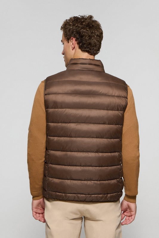 Unsere Herrenweste Chase zeichnet sich durch ein modernes und funktionelles Design aus. Die leichte Steppung wärmt, ohne den Komfort zu beeinträchtigen. Sie ist ohne Kapuze und mit Reißverschluss ausgestattet und verfügt über zwei Seitentaschen und eine Innentasche mit Reißverschluss für zusätzliche Funktionalität. Das Kleidungsstück ist wasserabweisend, jedoch nicht völlig wasserdicht, was es zu einer perfekten Wahl für eine Vielzahl von Wetterbedingungen macht. Unser neuer gummierter, farblich angepasster Rigby Go Aufnäher auf der Brust, die schrägen Einsätze und das Futter in Kontrastfarbe machen dieses Kleidungsstück zu einem modernen Klassiker.