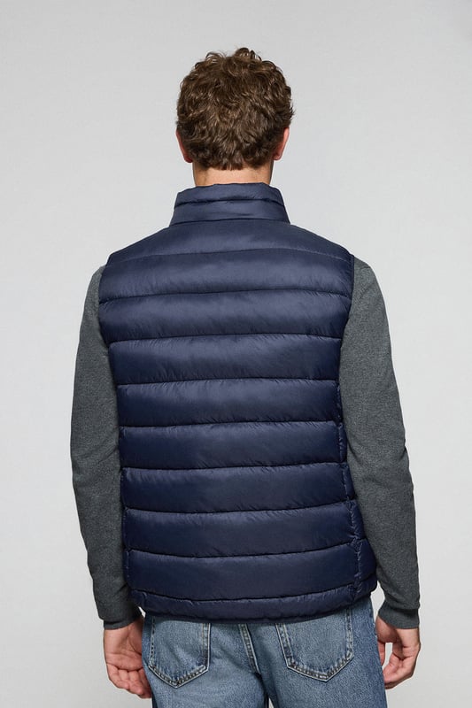 Unsere Herrenweste Chase zeichnet sich durch ein modernes und funktionelles Design aus. Die leichte Steppung wärmt, ohne den Komfort zu beeinträchtigen. Sie ist ohne Kapuze und mit Reißverschluss ausgestattet und verfügt über zwei Seitentaschen und eine Innentasche mit Reißverschluss für zusätzliche Funktionalität. Das Kleidungsstück ist wasserabweisend, jedoch nicht völlig wasserdicht, was es zu einer perfekten Wahl für eine Vielzahl von Wetterbedingungen macht. Unser neuer gummierter, farblich angepasster Rigby Go Aufnäher auf der Brust, die schrägen Einsätze und das Futter in Kontrastfarbe machen dieses Kleidungsstück zu einem modernen Klassiker.