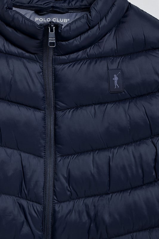 Unsere Herrenweste Chase zeichnet sich durch ein modernes und funktionelles Design aus. Die leichte Steppung wärmt, ohne den Komfort zu beeinträchtigen. Sie ist ohne Kapuze und mit Reißverschluss ausgestattet und verfügt über zwei Seitentaschen und eine Innentasche mit Reißverschluss für zusätzliche Funktionalität. Das Kleidungsstück ist wasserabweisend, jedoch nicht völlig wasserdicht, was es zu einer perfekten Wahl für eine Vielzahl von Wetterbedingungen macht. Unser neuer gummierter, farblich angepasster Rigby Go Aufnäher auf der Brust, die schrägen Einsätze und das Futter in Kontrastfarbe machen dieses Kleidungsstück zu einem modernen Klassiker.