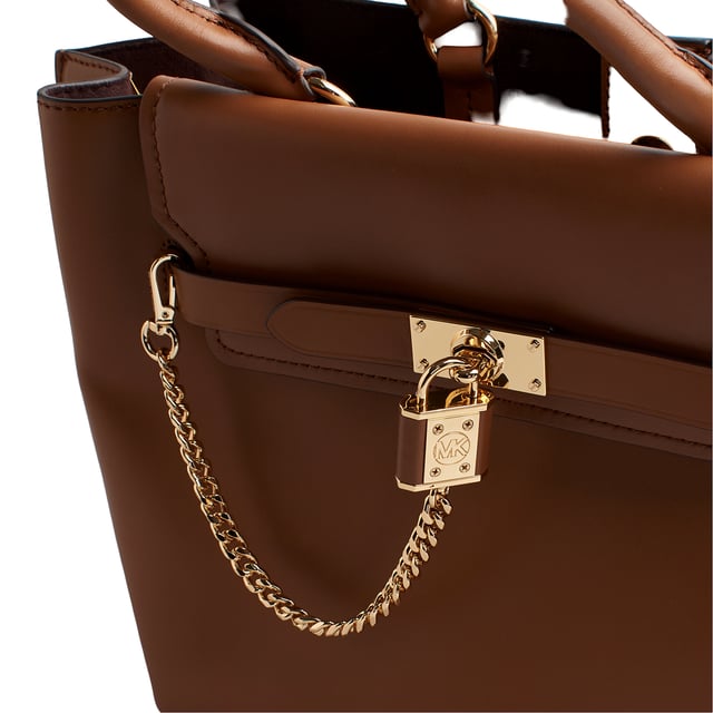 Our Michael Kors Hamilton Legacy satchel is as functional as it is bold, destined to become an icon. Crafted from luxurious leather with adjustable side gussets, it features a sophisticated link chain pendant that adds a decorative touch.

 Details:

 - Accessory Type: Satchel Bag.
 - Material: Cowhide.
 - Texture: Smooth.
 - Hardware: Gold tone.
 - Interior details: 3-slot plain back pocket, 3 compartments: 1 with zipper closure.
 - Exterior details: Decorative chain with pendant, decorative side bows.
 - Detachable and adjustable shoulder strap for carrying.
 - Top handles to carry as a handbag.
 - Closure: Main zipper.

 Each of Michael Kors' accessories collections boasts a strong identity, offering a fresh mix of timeless trends, colors, and silhouettes, combined with urban style and attitude. Each women's satchel designed by Michael Kors is an affordable luxury with a touch of modern, unexpected, and comfortable glamour, offering a piece for every occasion.
 Measures: 39.4 cm x 24.1 cm x 15.2 cm
 Composition: 100% Leather
 Care:
Clean with a soft, dry cloth.
 Avoid prolonged exposure to the sun and humidity.
 Do not apply abrasive products to the skin.
 Avoid contact with liquids and rough surfaces.
