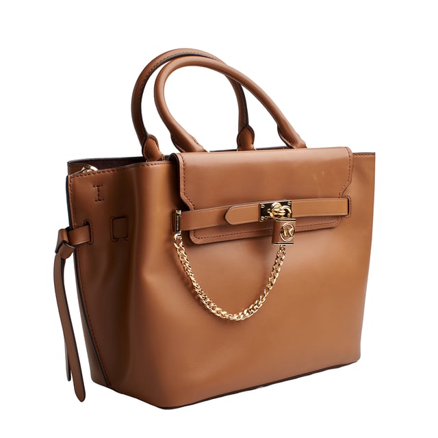 Our Michael Kors Hamilton Legacy satchel is as functional as it is bold, destined to become an icon. Crafted from luxurious leather with adjustable side gussets, it features a sophisticated link chain pendant that adds a decorative touch.

 Details:

 - Accessory Type: Satchel Bag.
 - Material: Cowhide.
 - Texture: Smooth.
 - Hardware: Gold tone.
 - Interior details: 3-slot plain back pocket, 3 compartments: 1 with zipper closure.
 - Exterior details: Decorative chain with pendant, decorative side bows.
 - Detachable and adjustable shoulder strap for carrying.
 - Top handles to carry as a handbag.
 - Closure: Main zipper.

 Each of Michael Kors' accessories collections boasts a strong identity, offering a fresh mix of timeless trends, colors, and silhouettes, combined with urban style and attitude. Each women's satchel designed by Michael Kors is an affordable luxury with a touch of modern, unexpected, and comfortable glamour, offering a piece for every occasion.
 Measures: 39.4 cm x 24.1 cm x 15.2 cm
 Composition: 100% Leather
 Care:
Clean with a soft, dry cloth.
 Avoid prolonged exposure to the sun and humidity.
 Do not apply abrasive products to the skin.
 Avoid contact with liquids and rough surfaces.