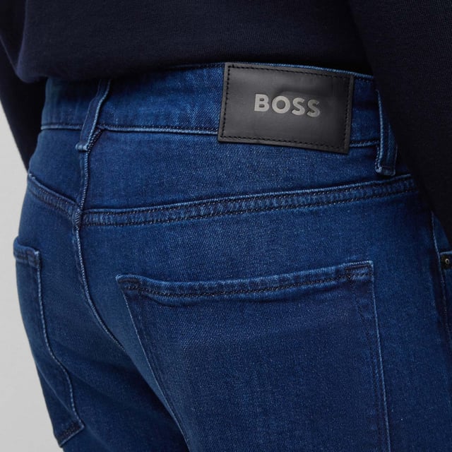 Men's Boss Maine Slim-Fit Jeans. These classic straight-leg jeans, made from premium cotton, feature five pockets, belt loops, and a zip fly with button fastening. Finished in a solid color with open cuffs and Boss branding, they offer both comfort and sophistication. Material: 60% Cotton, 39% Lyocell, 1% Elastane. Ref: 50496199430.