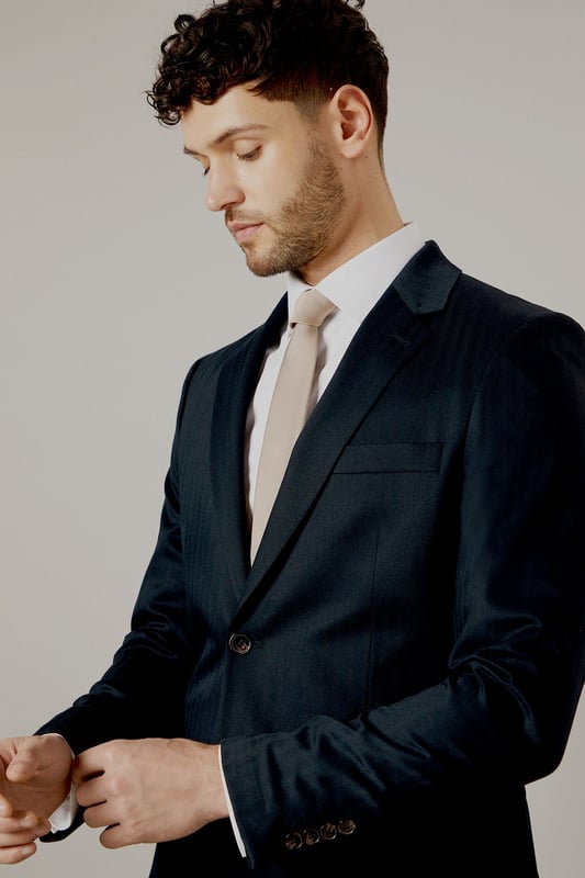 Tailored fit for a refined silhouette
        Distinctive herringbone pattern adds texture
        Notched lapels for classic sophistication
        Two-button front closure for versatile styling
        Flap pockets and a chest welt pocket for functionality
    
    This Burton herringbone suit jacket is the epitome of smart, sophisticated style. The tailored fit sculpts your silhouette while offering ease of movement, perfect for the modern gent who appreciates classic design with a contemporary edge. Ideal for a range of occasions, from important business meetings to smart-casual events at the local pub. Pair with matching trousers and a crisp white shirt for a complete look, or dress it down with dark denim and a light jumper for a more relaxed ensemble. The versatile nature of this jacket makes it a staple for any wardrobe, easily transitioning from day to night. Whether you're heading to the office, attending a wedding, or meeting friends for a posh night out, this jacket will ensure you look polished and put-together.
