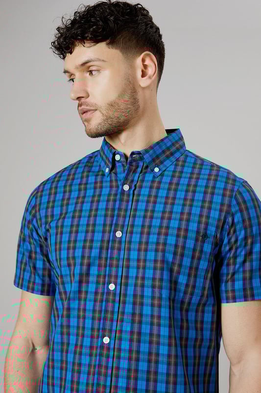 Vibrant tartan check pattern in bright blue tones
        Short sleeve design for warm-weather comfort
        Button-down collar for a smart-casual look
        Woven cotton fabric for breathability
        Versatile fit suitable for various body types
    
    This Maine short sleeve shirt presents a perfect blend of casual charm and smart styling. The eye-catching tartan check pattern in bright blue hues adds a pop of colour to your wardrobe, making it an ideal choice for those seeking to inject some personality into their everyday attire. Whether you're heading to a family barbecue or a casual Friday at the office, this shirt offers versatility in spades. Pair it with dark wash jeans and white trainers for a laid-back look, or dress it up with chinos and loafers for a more polished ensemble. The button-down collar adds a touch of refinement, while the short sleeves keep you cool and comfortable during warmer days. Crafted from woven cotton, this shirt ensures breathability and ease of movement, making it a go-to option for long summer days or relaxed weekend outings. Its adaptable fit flatters various body types, making it a wardrobe staple that you'll reach for time and time again.