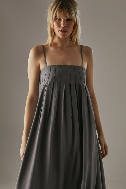 Strappy design with delicate shoulder straps
        Seam detail on bodice creating a pleated effect
        Bubble hem for a playful silhouette
        Midi length for versatile styling
        Relaxed fit through the body for effortless comfort
    
    This strappy seam detail bubble midi sundress from Warehouse is the epitome of casual chic. Perfect for those laid-back summer days, this dress combines comfort with style. The pleated bodice adds texture and interest, while the bubble hem creates a playful, feminine silhouette. Pair it with flat sandals and a woven tote for a relaxed daytime look, or dress it up with wedges and statement earrings for an alfresco dinner. The versatile midi length makes it suitable for various occasions, from family gatherings to casual brunches with friends. Layer with a denim jacket for cooler evenings or style with a wide-brimmed hat for a touch of glamour at outdoor events. This dress is a wardrobe essential that effortlessly transitions from day to night, embodying the confident and edgy spirit of the Warehouse brand.