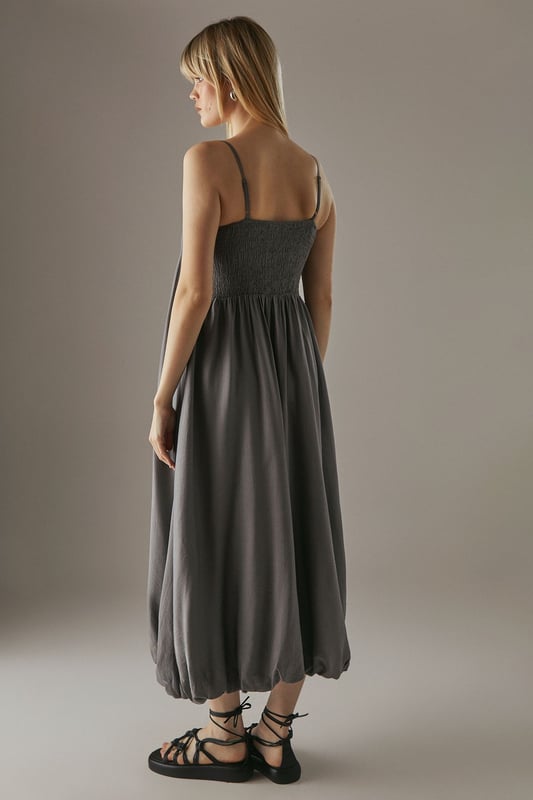 Strappy design with delicate shoulder straps
        Seam detail on bodice creating a pleated effect
        Bubble hem for a playful silhouette
        Midi length for versatile styling
        Relaxed fit through the body for effortless comfort
    
    This strappy seam detail bubble midi sundress from Warehouse is the epitome of casual chic. Perfect for those laid-back summer days, this dress combines comfort with style. The pleated bodice adds texture and interest, while the bubble hem creates a playful, feminine silhouette. Pair it with flat sandals and a woven tote for a relaxed daytime look, or dress it up with wedges and statement earrings for an alfresco dinner. The versatile midi length makes it suitable for various occasions, from family gatherings to casual brunches with friends. Layer with a denim jacket for cooler evenings or style with a wide-brimmed hat for a touch of glamour at outdoor events. This dress is a wardrobe essential that effortlessly transitions from day to night, embodying the confident and edgy spirit of the Warehouse brand.