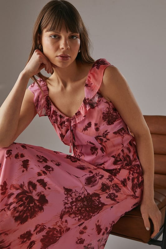 Chiffon fabric with floral print for a light, airy feel
        Double-layered design for added movement and depth
        Ruffle detailing along neckline and shoulders
        Midi length for versatile styling options
        Open back design with delicate ruffle trim
    
    This enchanting midi dress radiates effortless femininity with its flowing chiffon fabric and captivating floral print. The double-layered design adds a touch of sophistication, while the ruffle detailing along the neckline and shoulders creates a romantic silhouette. Perfect for a variety of casual occasions, this dress can be styled with flat sandals for a relaxed daytime look or dressed up with heeled mules for evening gatherings. The open back with ruffle trim adds an unexpected twist, making it an ideal choice for garden parties or summer weddings. Layer with a lightweight cardigan for cooler evenings or pair with statement earrings to enhance its feminine charm. This versatile piece from Warehouse embodies confidence and style, making it a must-have addition to your wardrobe for those moments when you want to feel both comfortable and effortlessly chic.