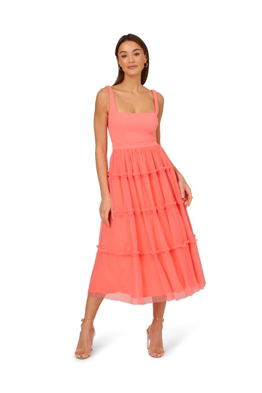 Modern fabric mixes make this classic fit and flare dress a sweet look. This midi dress features a fitted bodice with tank straps, a square neckline, and a tiered skirt. Fully lined, the bodice is crafted from a knit fabrication while the skirt is overlaid in mesh for added sweep. Pockets and a square back with centre zip closure complete this delightful party dress. Styled with nude heels and sparkling accessories, this midi dress is a timeless look from wedding guest duty to cocktail parties