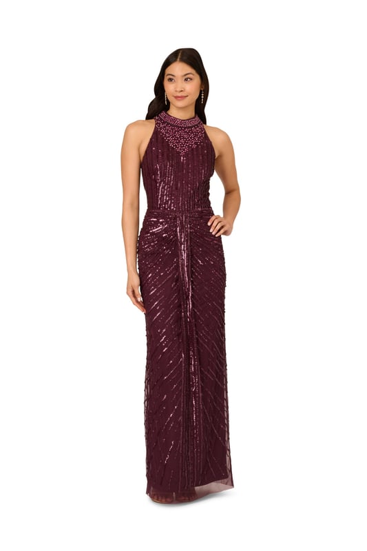 Deco details make this halter gown outshine the competition. This formal dress features a halter bodice, mock neckline, and a column skirt. Draped details at the skirt adds drama to this sleeveless gown. Crafted from mesh knit fabric and embellished with a chic mix of sequins, beading and gems in a design that accentuates the figure. A hidden zipper closure completes this beaded gown. Nude heels and a satin clutch are all this black-tie dress needs to shine all night long.