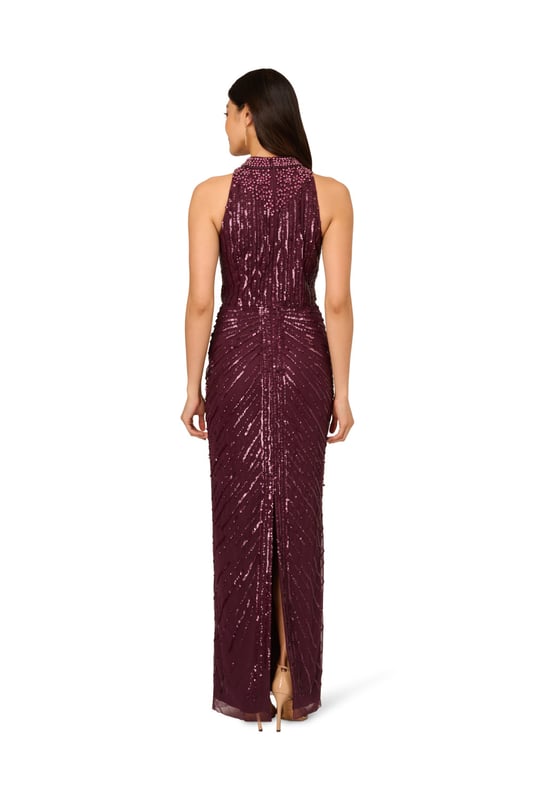Deco details make this halter gown outshine the competition. This formal dress features a halter bodice, mock neckline, and a column skirt. Draped details at the skirt adds drama to this sleeveless gown. Crafted from mesh knit fabric and embellished with a chic mix of sequins, beading and gems in a design that accentuates the figure. A hidden zipper closure completes this beaded gown. Nude heels and a satin clutch are all this black-tie dress needs to shine all night long.