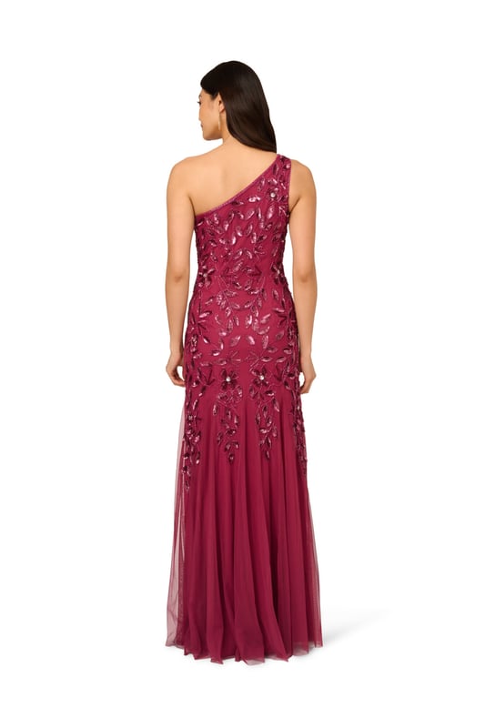 Brighten every ball room you step into in this one shoulder mermaid gown. This formal dress features a fitted bodice, one shoulder neckline, and a mermaid skirt with godet pleats. Crafted from knit mesh that is adorned with stunning sequin beaded florals and the edges are trimmed with lines of tight beading that fades mid-skirt. A hidden zipper closure at the centre back completes this black-tie dress.