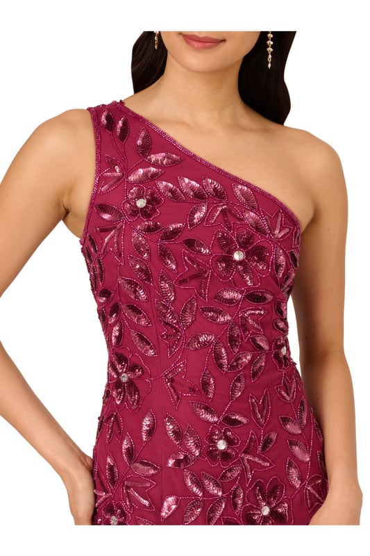 Brighten every ball room you step into in this one shoulder mermaid gown. This formal dress features a fitted bodice, one shoulder neckline, and a mermaid skirt with godet pleats. Crafted from knit mesh that is adorned with stunning sequin beaded florals and the edges are trimmed with lines of tight beading that fades mid-skirt. A hidden zipper closure at the centre back completes this black-tie dress.