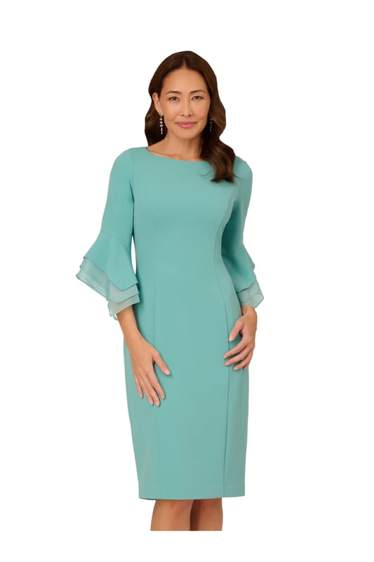 Dressed up meets versatile in this timeless sheath dress. This midi dress features a boat neckline, fitted silhouette through the body, and tiered three-quarter bell sleeves with organza accents. Crafted using knit crepe, this day dress has some stretch and no waist seam for a comfortable fit. A zipper back closure and a single pleat at the center back of the skirt hem completes the design.
