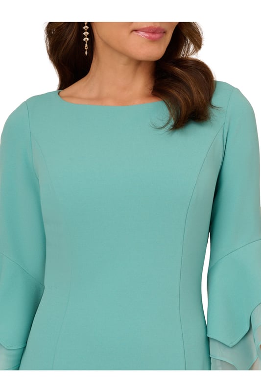 Dressed up meets versatile in this timeless sheath dress. This midi dress features a boat neckline, fitted silhouette through the body, and tiered three-quarter bell sleeves with organza accents. Crafted using knit crepe, this day dress has some stretch and no waist seam for a comfortable fit. A zipper back closure and a single pleat at the center back of the skirt hem completes the design.