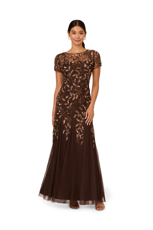 Our long and romantic gown dazzles with all-over handsewn beading in a feminine floral pattern that catches the light with every twirl. A streamlined silhouette is eased with the mermaid skirt with godets to create the right amount of movement. Our iconic and flattering no waist seam, sheer illusion yoke and cap sleeves. Sleek back zip closure.