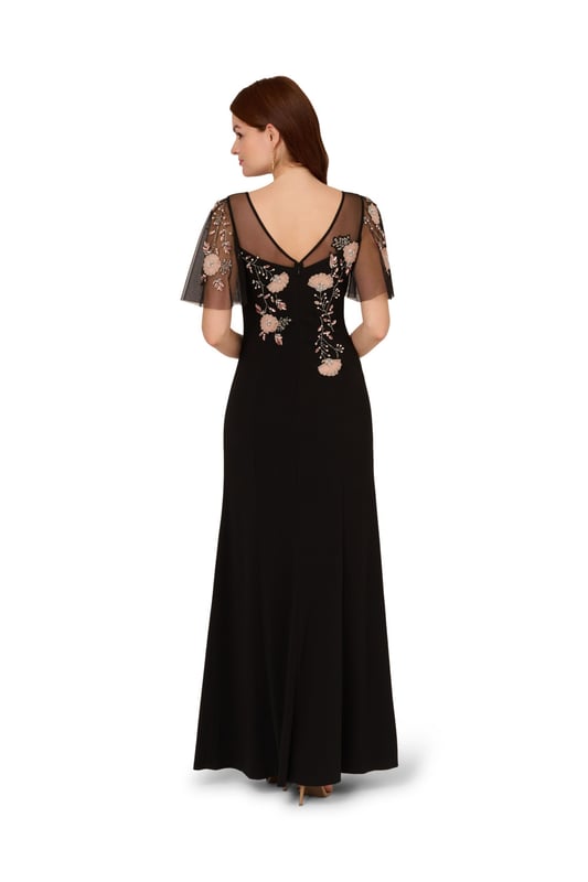 Beaded Crepe Long Dress Lean into formal season with this sweetly beaded gown. This formal dress features a fitted bodice with boat neckline, a sheer yoke that gives a sweetheart neckline illusion, sheer flutter sleeves and a mermaid skirt with thigh-high slit. Crafted from crepe fabric through the body, this dress has knit mesh at the bodice and sleeves that is embellished with beautiful sequin beaded florals. A hidden zipper closure at the sheer v-back completes this black-tie dress. Styled with neutral accessories that let the floral beading shine, this flutter short sleeve gown is a romantic look.