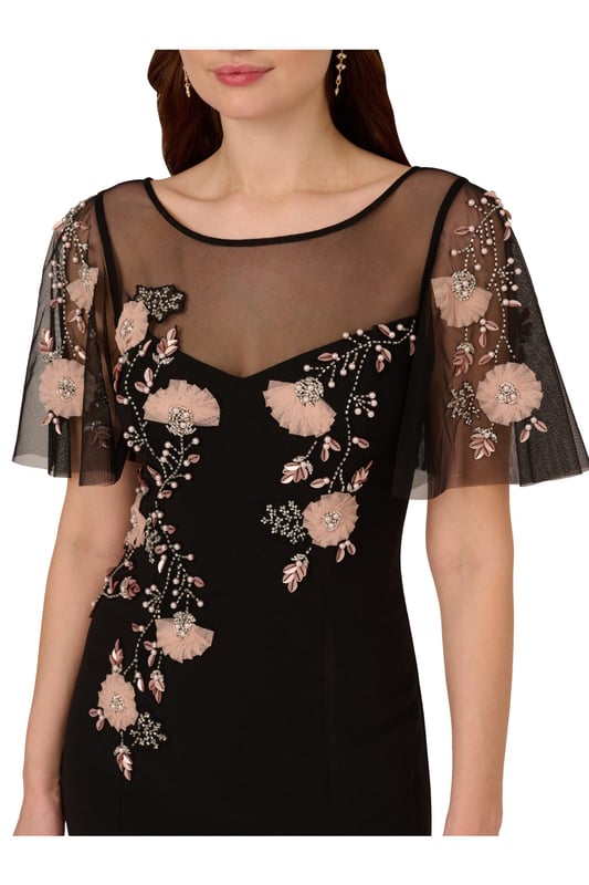 Beaded Crepe Long Dress Lean into formal season with this sweetly beaded gown. This formal dress features a fitted bodice with boat neckline, a sheer yoke that gives a sweetheart neckline illusion, sheer flutter sleeves and a mermaid skirt with thigh-high slit. Crafted from crepe fabric through the body, this dress has knit mesh at the bodice and sleeves that is embellished with beautiful sequin beaded florals. A hidden zipper closure at the sheer v-back completes this black-tie dress. Styled with neutral accessories that let the floral beading shine, this flutter short sleeve gown is a romantic look.