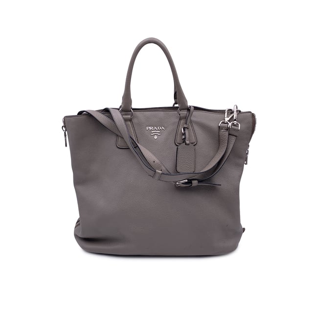VINTAGE, UVP WIE NEU  
Schöne PRADA Tote-Bag aus strukturiertem Leder in Grau Taupe. Sie verfügt über doppelte, runde Obergriffe und einen verstellbaren sowie abnehmbaren Schultergurt. Auf der Vorderseite befindet sich die PRADA-Beschriftung in Silbermetall. Oberer Reißverschlussverschluss. 4 Fuß aus Metall am Boden. Die Tasche hat ein Hauptfach. Das Innere ist vollständig mit dem charakteristischen PRADA-Stoff ausgekleidet. 1 interne Reißverschlusstasche und 1 offene Tasche innen. Vier Metallfüße am Boden für Stil und Schutz. 'PRADA Milano'-Tag innen, kleines Etikett mit Zahlen in der Innenstasche. Zustand Bewertung: B - SEHR GUTER ZUSTAND  
Zustandsdetails: Einige kleine Kratzer (mit kleinen weißen Stellen) auf dem Leder aufgrund normaler Nutzung. Ein paar schwarze Flecken auf dem Leder durch normale Nutzung. Einige Gebrauchsspuren an den unteren Ecken. Einige leichte Kratzer auf der Oberfläche des Beschlags. Bitte überprüfen Sie die Fotos sorgfältig und fragen Sie, wenn Sie weitere Details benötigen oder zweifeln haben.  
Maße (cm):  
Tiefe: 15,2  
Höhe: 34,3  
Länge: 36,8  
Weitere Details: Staubbeutel? Ja  
Schlüssel? Nein  
Box? Nein  
Maße: Breite: 152 mm, Länge: 368 mm, Höhe: 343 mm