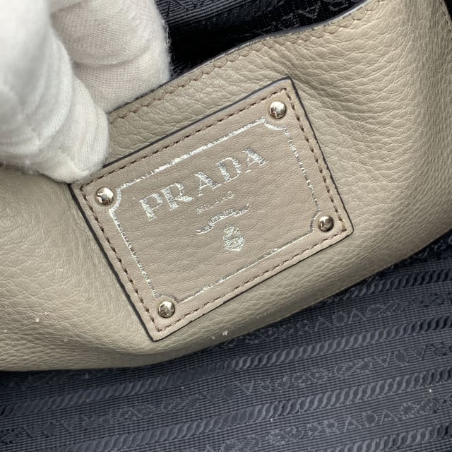 VINTAGE, UVP WIE NEU  
Schöne PRADA Tote-Bag aus strukturiertem Leder in Grau Taupe. Sie verfügt über doppelte, runde Obergriffe und einen verstellbaren sowie abnehmbaren Schultergurt. Auf der Vorderseite befindet sich die PRADA-Beschriftung in Silbermetall. Oberer Reißverschlussverschluss. 4 Fuß aus Metall am Boden. Die Tasche hat ein Hauptfach. Das Innere ist vollständig mit dem charakteristischen PRADA-Stoff ausgekleidet. 1 interne Reißverschlusstasche und 1 offene Tasche innen. Vier Metallfüße am Boden für Stil und Schutz. 'PRADA Milano'-Tag innen, kleines Etikett mit Zahlen in der Innenstasche. Zustand Bewertung: B - SEHR GUTER ZUSTAND  
Zustandsdetails: Einige kleine Kratzer (mit kleinen weißen Stellen) auf dem Leder aufgrund normaler Nutzung. Ein paar schwarze Flecken auf dem Leder durch normale Nutzung. Einige Gebrauchsspuren an den unteren Ecken. Einige leichte Kratzer auf der Oberfläche des Beschlags. Bitte überprüfen Sie die Fotos sorgfältig und fragen Sie, wenn Sie weitere Details benötigen oder zweifeln haben.  
Maße (cm):  
Tiefe: 15,2  
Höhe: 34,3  
Länge: 36,8  
Weitere Details: Staubbeutel? Ja  
Schlüssel? Nein  
Box? Nein  
Maße: Breite: 152 mm, Länge: 368 mm, Höhe: 343 mm