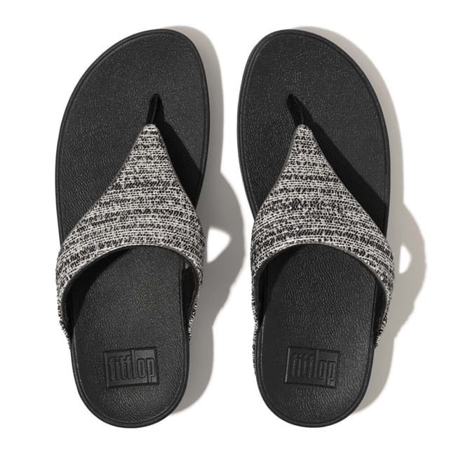 Women's Fit Flop Lulu Shimmerweave Toe-Post Sandals in Black FitFlop's bestselling Lulu sandals boast a timeless triangular vamp softly padded uppers and a soft microfibre toe post. Featuring FitFlop's Microwobbleboard™ midsoles for unbeatable comfort. This season in a sparkling finely ribbed glitz mesh (with metallic pearlised faux-leather side panels for extra lustre). Beautiful. Versatile. The sophisticated shimmer means these work with multiple looks - dress yours up or down wear day through to night.Ergonomically engineered to help optimize your body's alignment natural movement & energyLight pressure-diffusing Microwobbleboard midsole - triple-density cushioning follows 3 footstep stages (firm heel-soft middle-medium at toes)Natural arch supportAverage to wide fitGrip level 1 - everyday use-road treadThese shoes have been granted the APMA* Seal of Acceptance for footwear found to promote good foot health*American Podiatric Medical Association