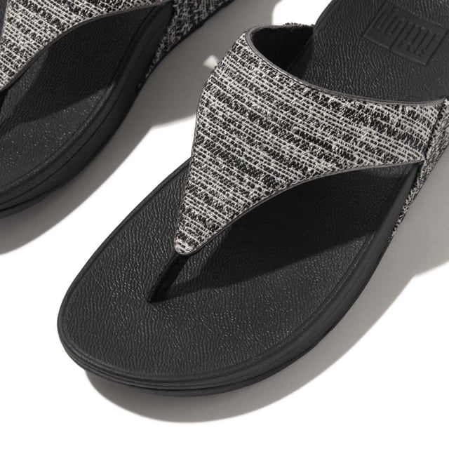 Women's Fit Flop Lulu Shimmerweave Toe-Post Sandals in Black FitFlop's bestselling Lulu sandals boast a timeless triangular vamp softly padded uppers and a soft microfibre toe post. Featuring FitFlop's Microwobbleboard™ midsoles for unbeatable comfort. This season in a sparkling finely ribbed glitz mesh (with metallic pearlised faux-leather side panels for extra lustre). Beautiful. Versatile. The sophisticated shimmer means these work with multiple looks - dress yours up or down wear day through to night.Ergonomically engineered to help optimize your body's alignment natural movement & energyLight pressure-diffusing Microwobbleboard midsole - triple-density cushioning follows 3 footstep stages (firm heel-soft middle-medium at toes)Natural arch supportAverage to wide fitGrip level 1 - everyday use-road treadThese shoes have been granted the APMA* Seal of Acceptance for footwear found to promote good foot health*American Podiatric Medical Association