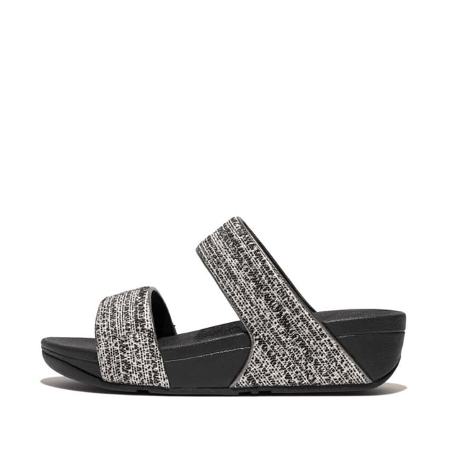 Women's Fit Flop Lulu Shimmerweave Sliders in Black De Lulu slippers van FitFlop zijn klassiekers. Blijvend populair, ze zijn zacht gevoerd en kunnen omhoog of omlaag gekleed worden. Ze staan op FitFlop's legendarische super dempende Microwobbleboard™ tussenzool. Dit seizoen uitgevoerd in een glinsterende structuurstof met een chique 'tweedy' uitstraling. Afgerand met metallic parelmoeren biezen van imitatieleer voor extra glans. Subtiel glinsterende sandalen die je overal bij kunt dragen en prachtig zijn van dag tot nacht.