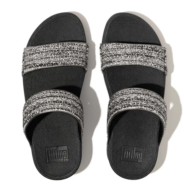 Women's Fit Flop Lulu Shimmerweave Sliders in Black De Lulu slippers van FitFlop zijn klassiekers. Blijvend populair, ze zijn zacht gevoerd en kunnen omhoog of omlaag gekleed worden. Ze staan op FitFlop's legendarische super dempende Microwobbleboard™ tussenzool. Dit seizoen uitgevoerd in een glinsterende structuurstof met een chique 'tweedy' uitstraling. Afgerand met metallic parelmoeren biezen van imitatieleer voor extra glans. Subtiel glinsterende sandalen die je overal bij kunt dragen en prachtig zijn van dag tot nacht.